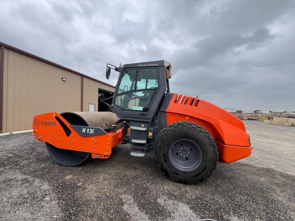 Orange single-drum road roller parked outdoors