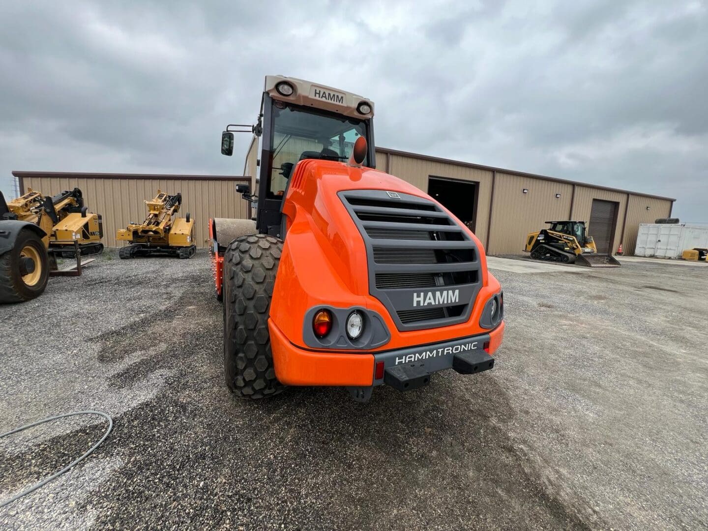 Orange HAMM compactor parked in equipment yard