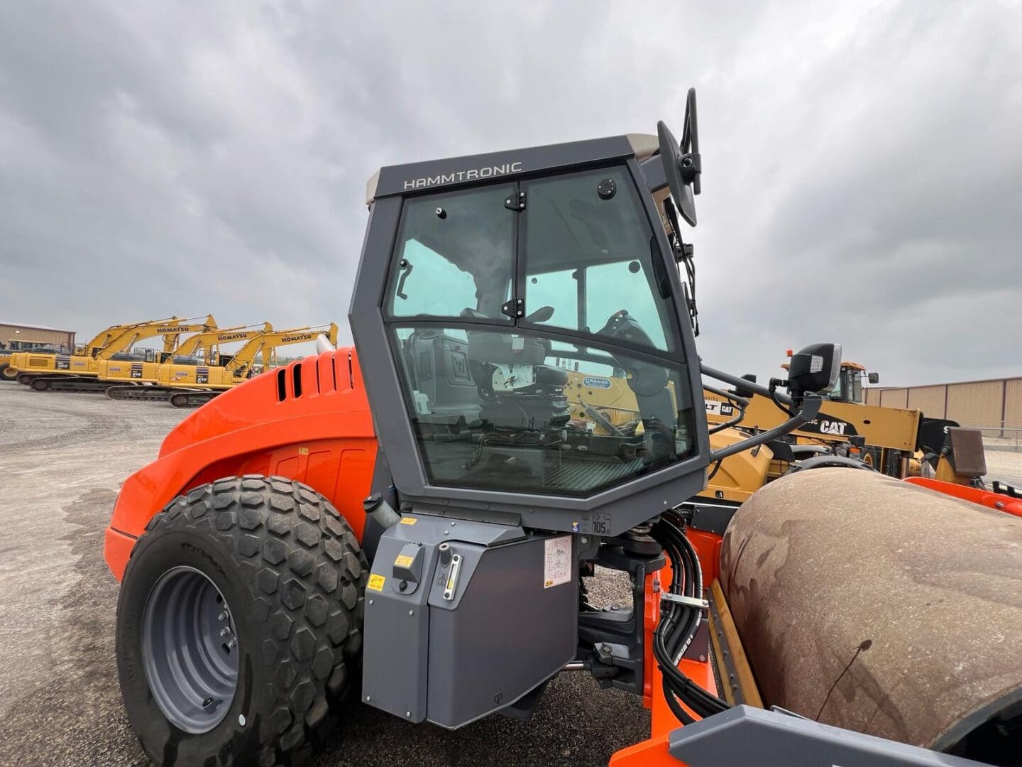 Orange construction roller compactor with glass cab