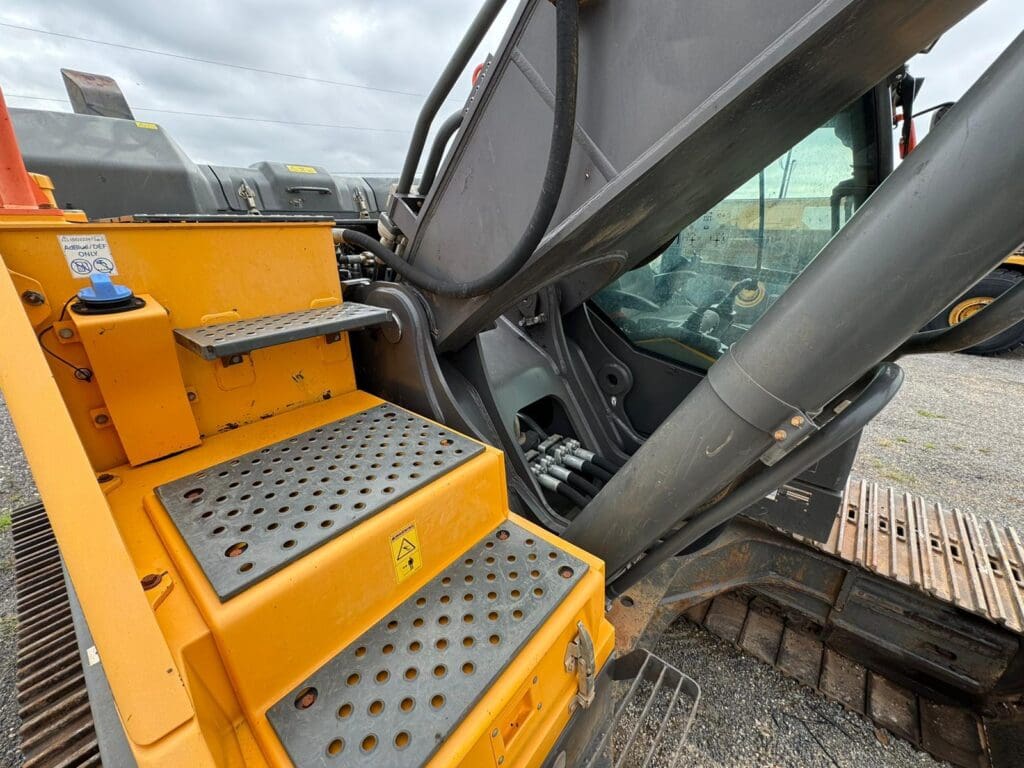Yellow excavator steps and hydraulic arm