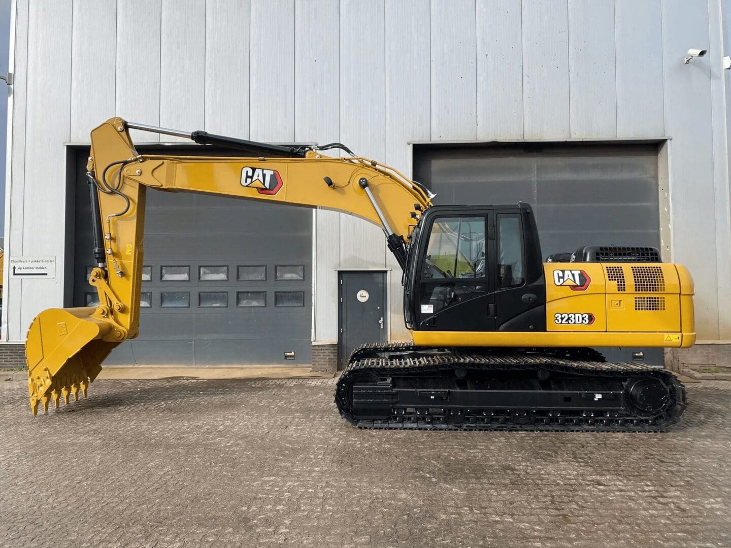 Yellow Caterpillar excavator parked by warehouse