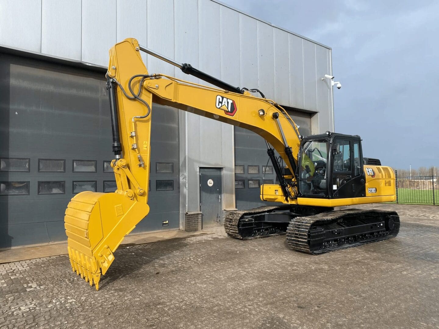 Yellow Caterpillar excavator parked outside warehouse