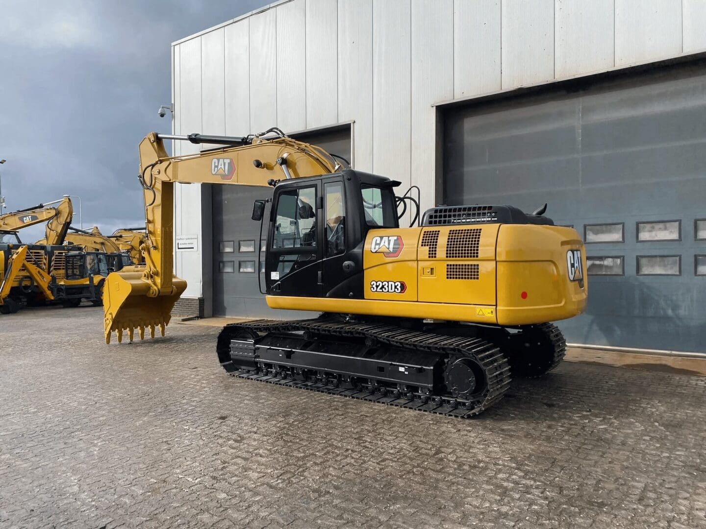 Yellow CAT excavator parked by industrial building