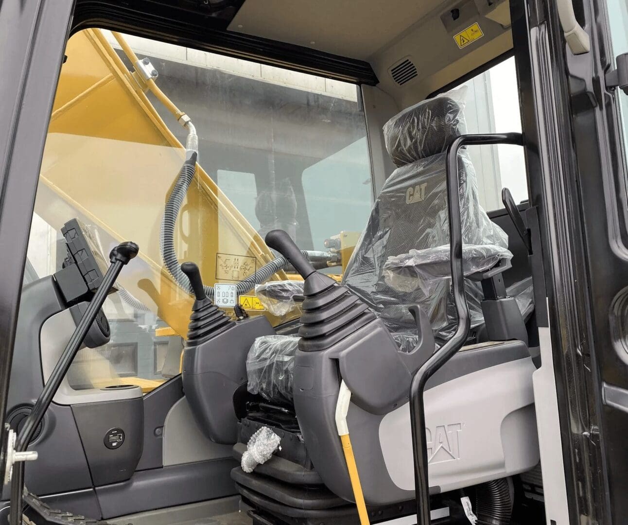 CAT excavator cab with plastic-wrapped seat