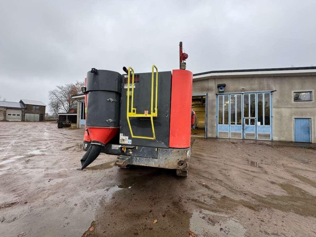 Red farm machine with chute parked outside