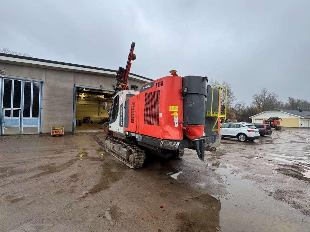 Red tracked construction machine parked outside garage