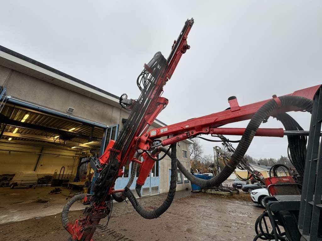 Red hydraulic drilling rig arm outside workshop