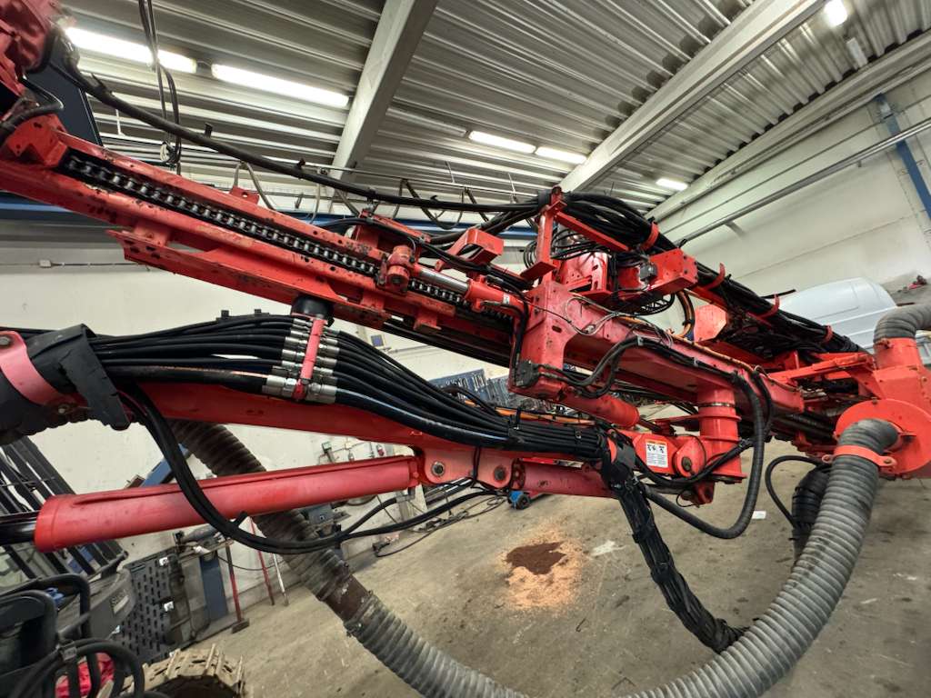 Red industrial hydraulic arm with hoses