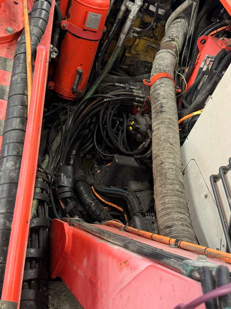 Red machinery compartment with hydraulic hoses and cables