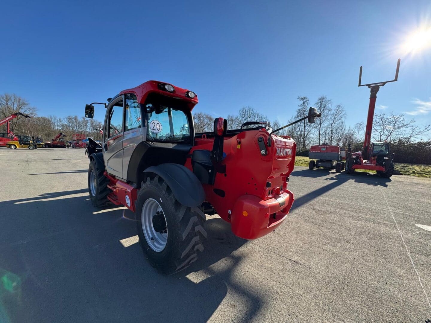 Red telehandler on paved lot under blue sky