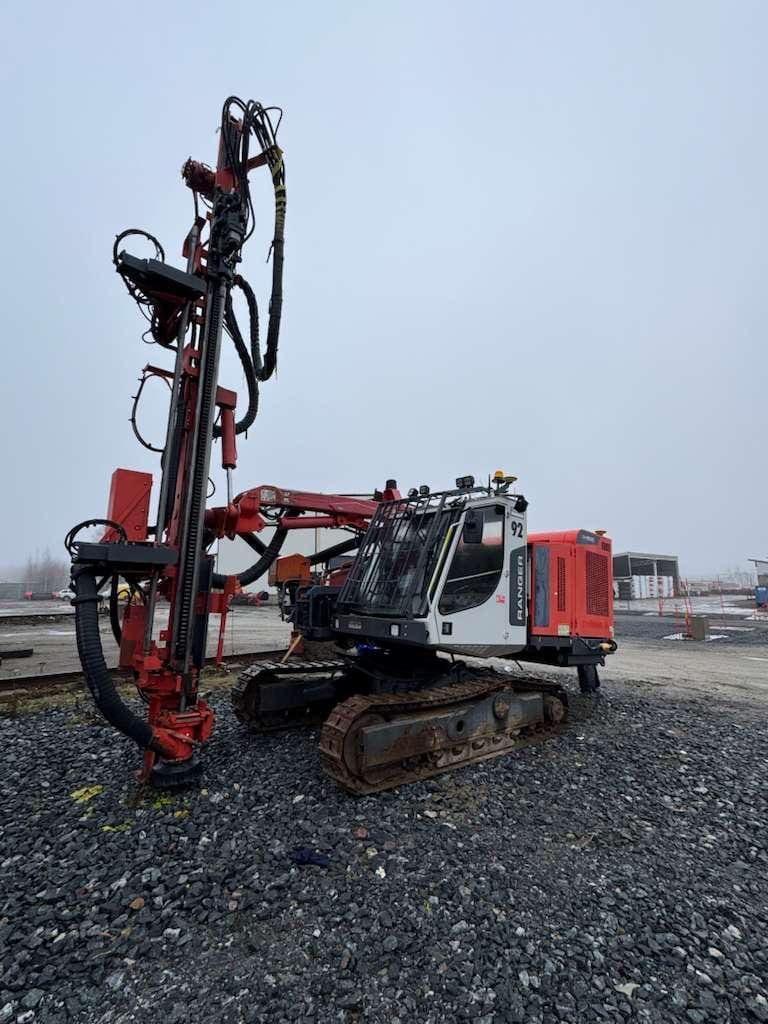 Red crawler-mounted drilling rig on gravel