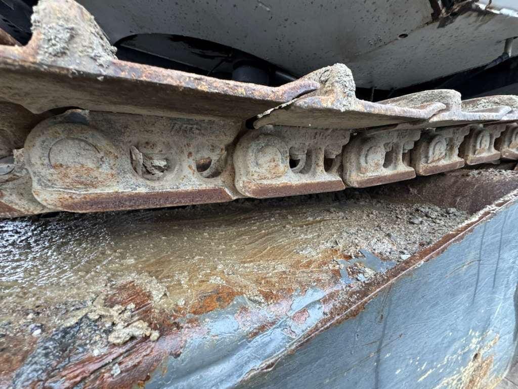 Rusted excavator track on muddy metal surface