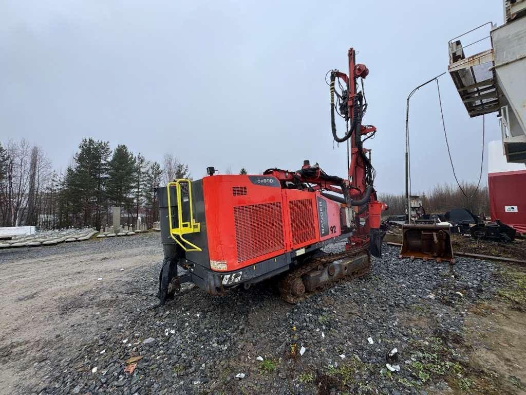 Red tracked drilling rig on gravel lot