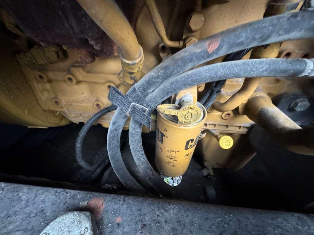 Yellow Caterpillar engine filter with attached hoses