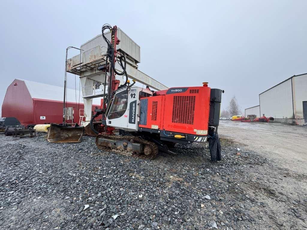 Red crawler drilling rig on gravel lot