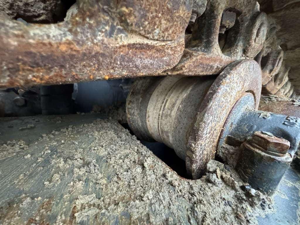 Rusty excavator track roller with mud buildup