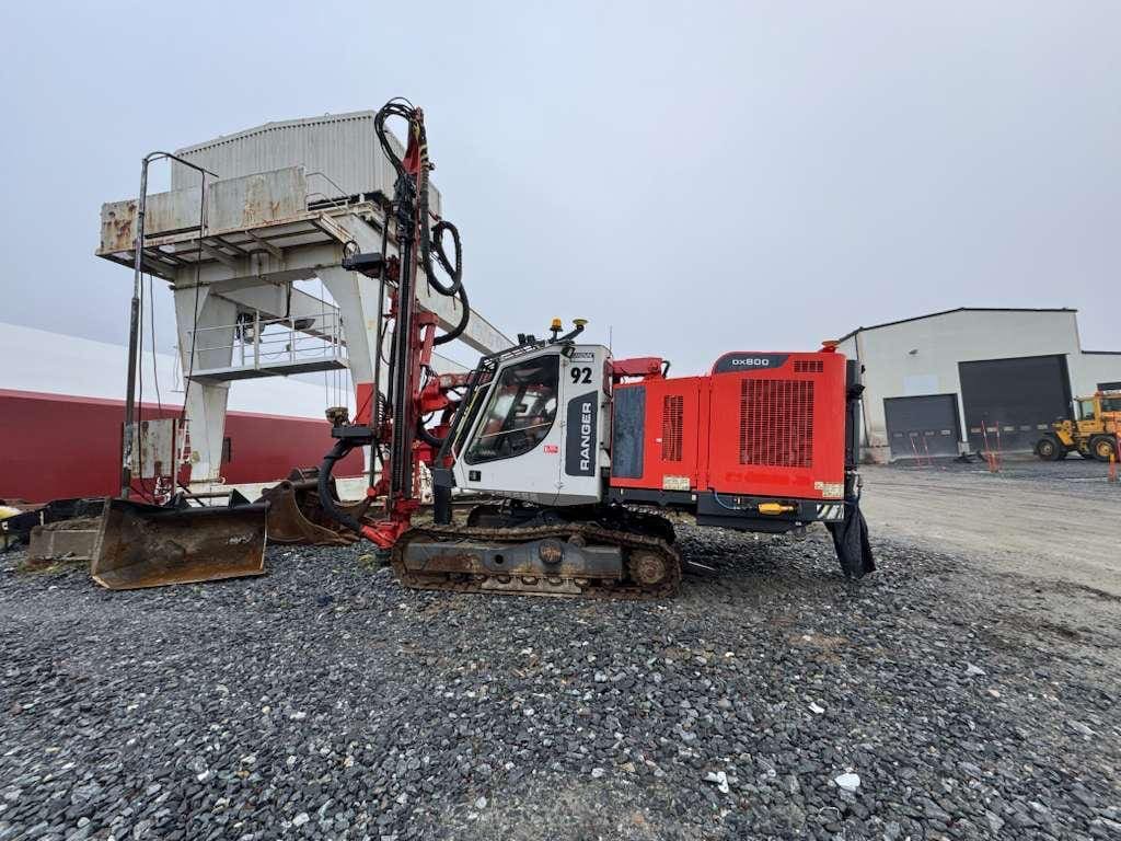 Red tracked drilling rig on gravel lot