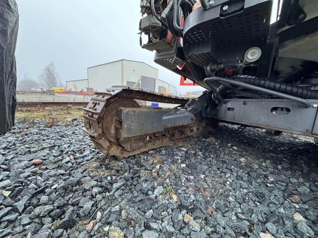 Excavator track resting on gravel surface
