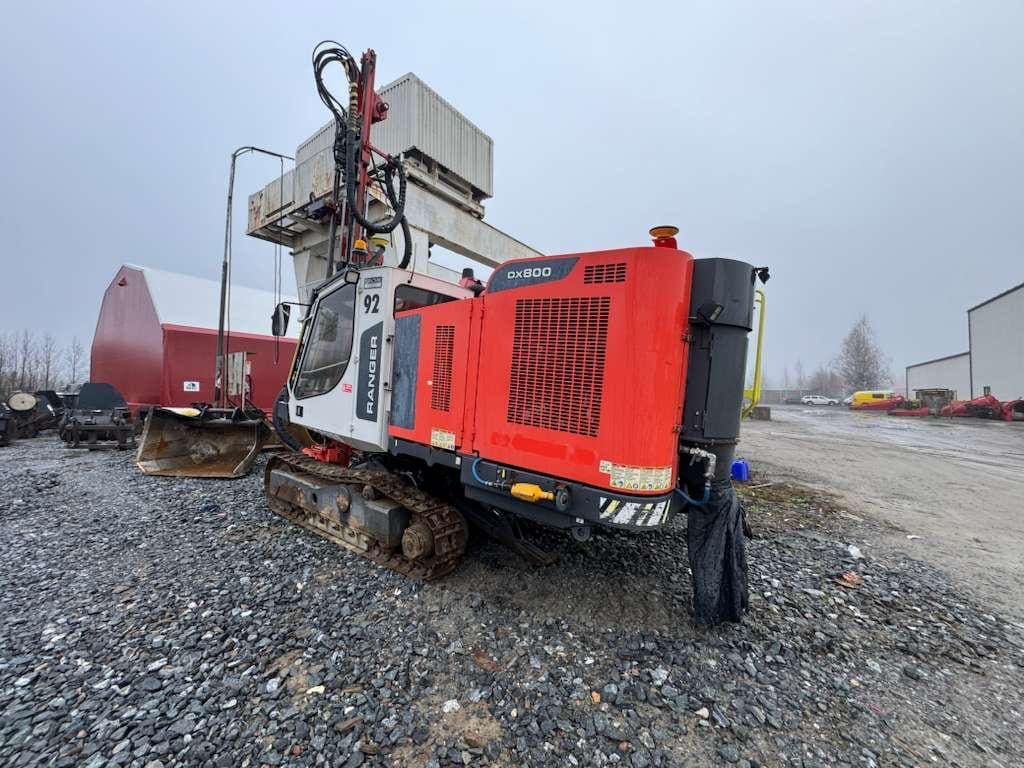 Red tracked drilling rig on gravel lot